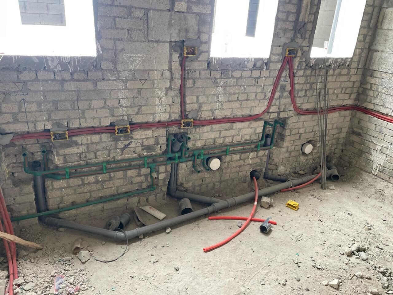 Water and drain pipes run along the wall under the windows